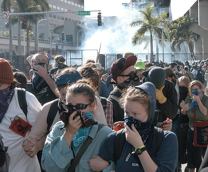 Protesters covering their faces with bandanas to protect themselves from riot police tear gas.
