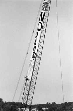 PHOTO COURTESY OF ORIN LANGELLE A climber on crane protests the construction of a hydroelectric dam on the Winooski River in solidarity with Vermont's Abenaki tribe. (1992