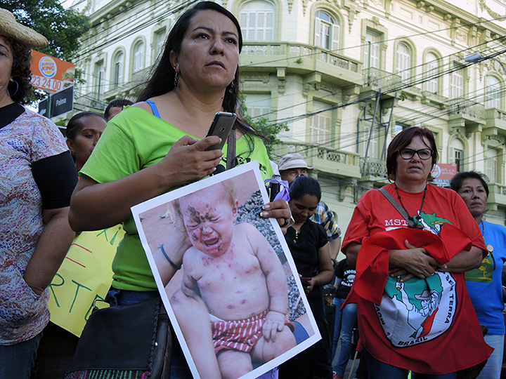 Woman holding photo of baby whose condition is blamed on Monsanto during a rally in Asunción, Paraguay, 3 December 2014.  PhotoLangelle.org